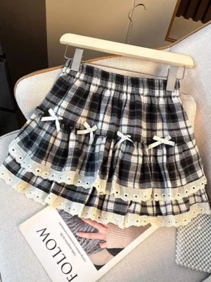Black and white tartan plaid tiered lolita mini skirt with eyelet lace trim and white ribbon bows featured on elegant wooden hanger
