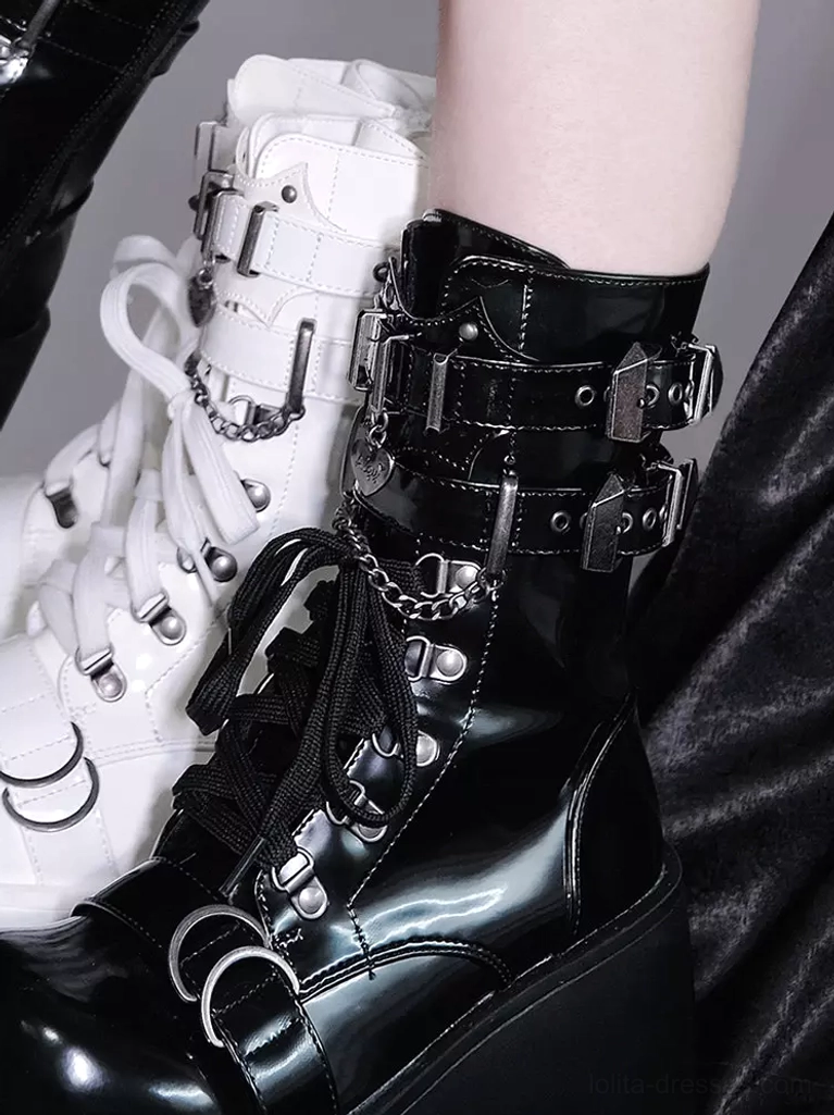 Black and white platform combat boots close-up side view with metal chain crescent-shaped hardware buckles and glossy leather chunky sole