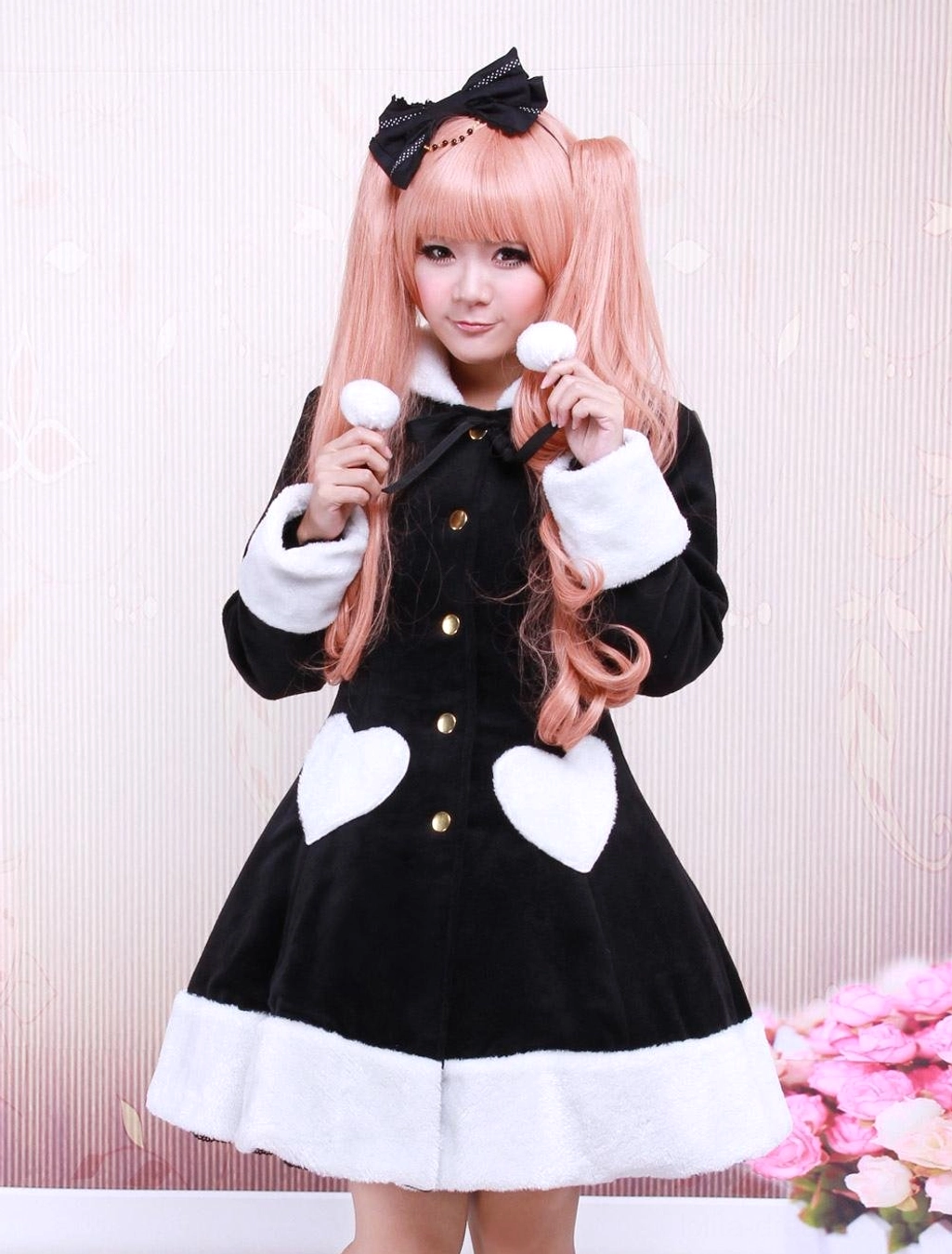Black wool lolita overcoat front view with fuzzy white trims, heart-shaped pockets, and pom-pom details worn by model with pink twin tails
