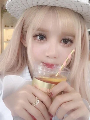 Pale blonde lolita wig with neat air bangs and soft long wavy texture on model in white woven hat holding drink, shop background, sweet lolita wig styling demonstration with ash blonde color