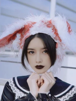 Bloody rabbit ear Gothic Lolita hat front close-up portrait view worn by model in black Gothic dress with white-red fuzzy fur and safety pin decorations