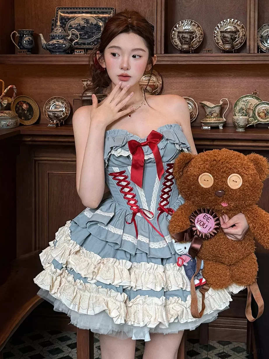 Front three-quarter view of blue ballet lolita dress in vintage tea room setting, featuring teddy bear backpack, red bow corset lace-up top, and ruffled mini skirt
