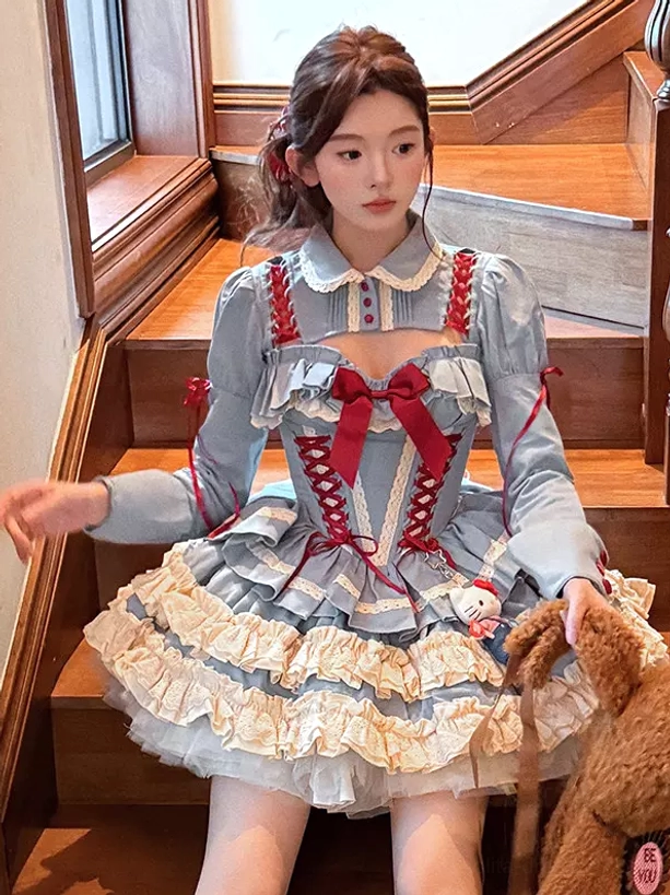 Front seated view of long-sleeve blue ballet lolita dress on wooden stairwell, showing Peter Pan collar, red bow lace-up corset, and layered ruffle skirt construction