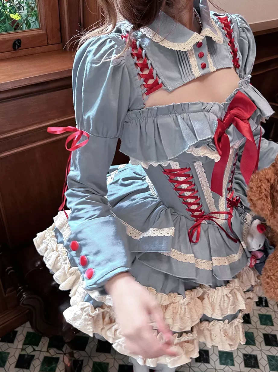 Close-up detail view of blue ballet lolita dress showing white lace cuffs, ruffle layers, and red ribbon bow accent details of the classic lolita design