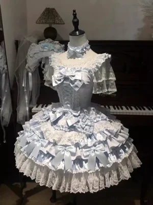 Ethereal blue classic lolita cake dress with cascading ruffles and satin bow displayed on mannequin with vintage piano background full-length front view
