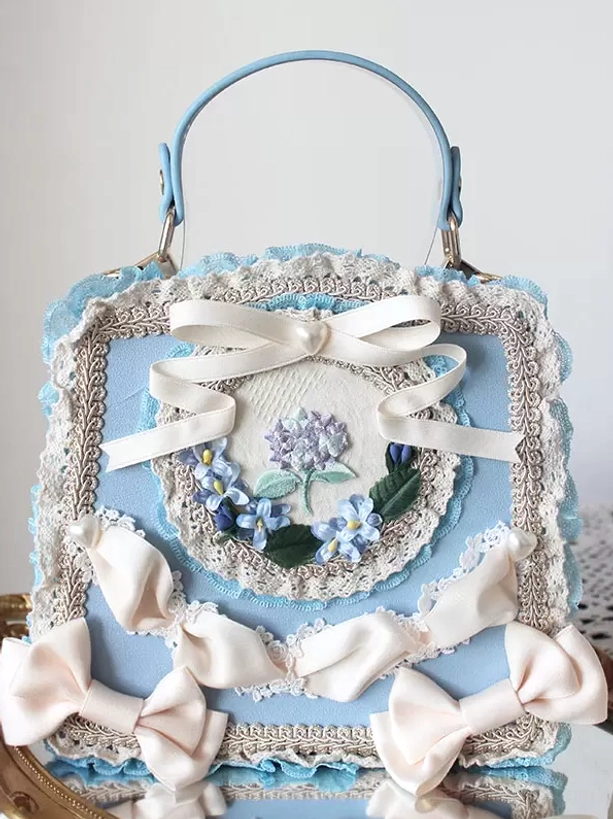 Blue-themed lolita PU leather handbag with ivory satin bows lace trims blue floral embroidery on lace table