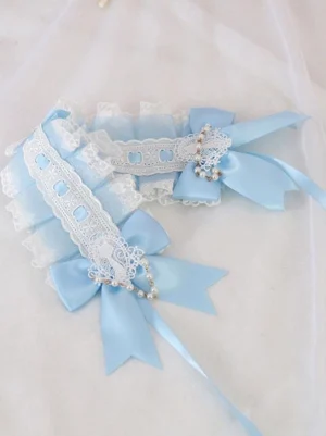 Flat-laid top-down view of blue lolita headband showing double satin bows, white lace trim, and beaded pearl details on sheer white fabric