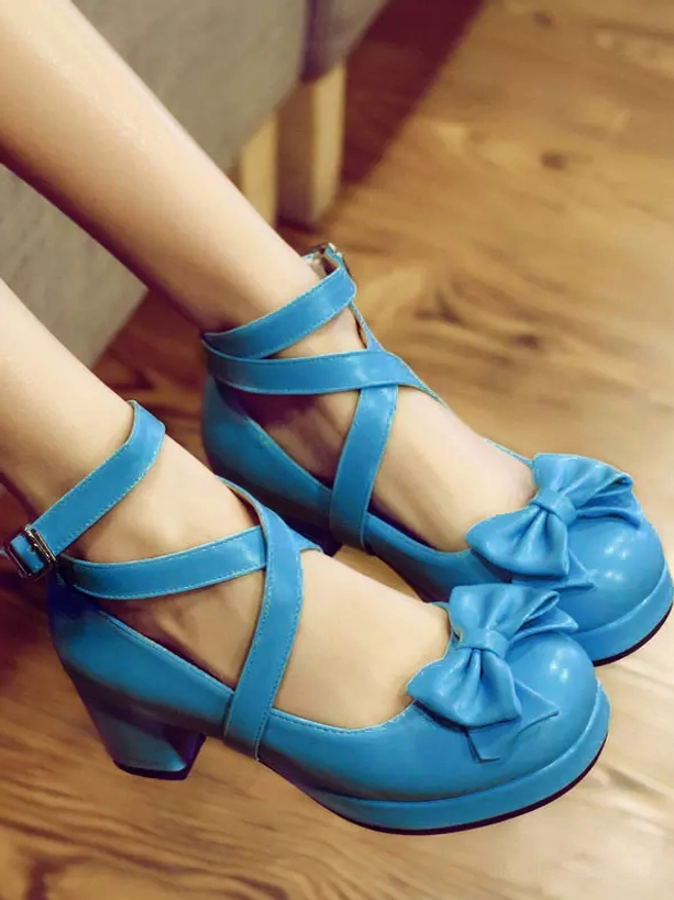 Bright blue PU leather Lolita chunky platform heels with round toe, cross ankle straps and bow decor close-up side view on wooden floor indoors