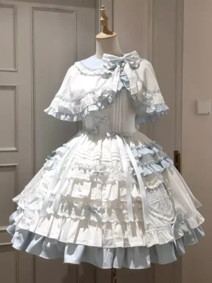 Blue and white sweet lolita cape dress set with cascading ruffled cape, front view on dress form showing layered ruffled skirt, structured corset bodice, delicate spaghetti straps, and prominent front bow embellishment