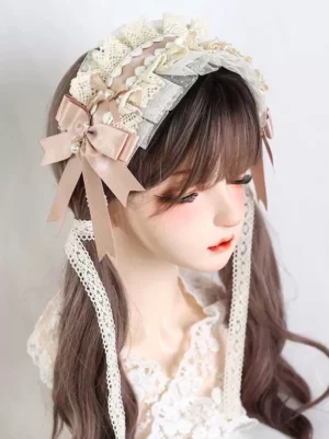 Blush pink satin bow sweet Lolita lace headdress with layered cream ruffles and pearl drop pendant, three-quarter side profile on mannequin