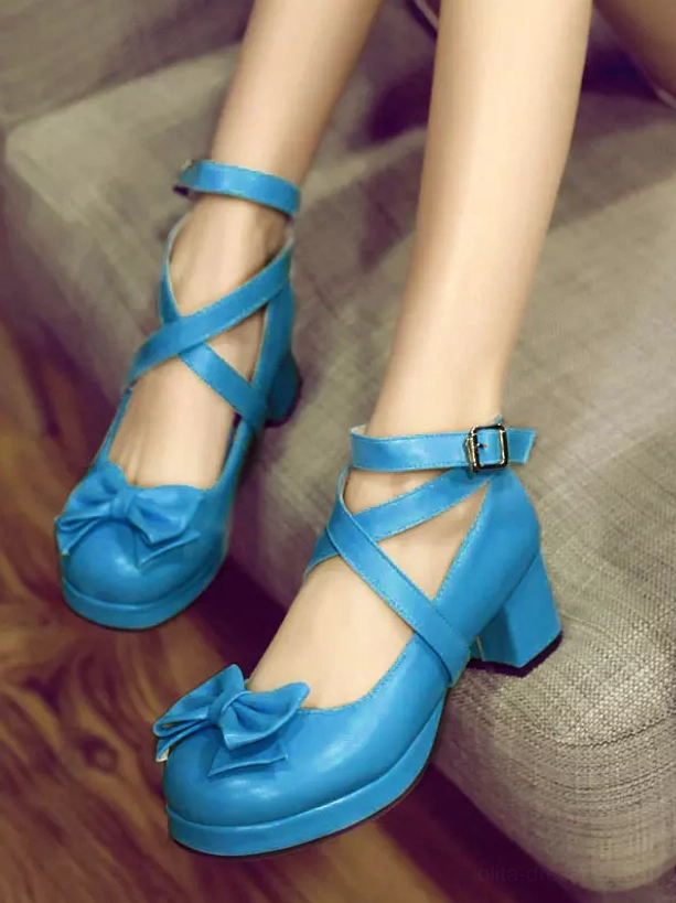 Bright blue Sweet Lolita platform shoes with cross ankle straps buckle closure and front bow decoration on fabric sofa display showing chunky heel profile