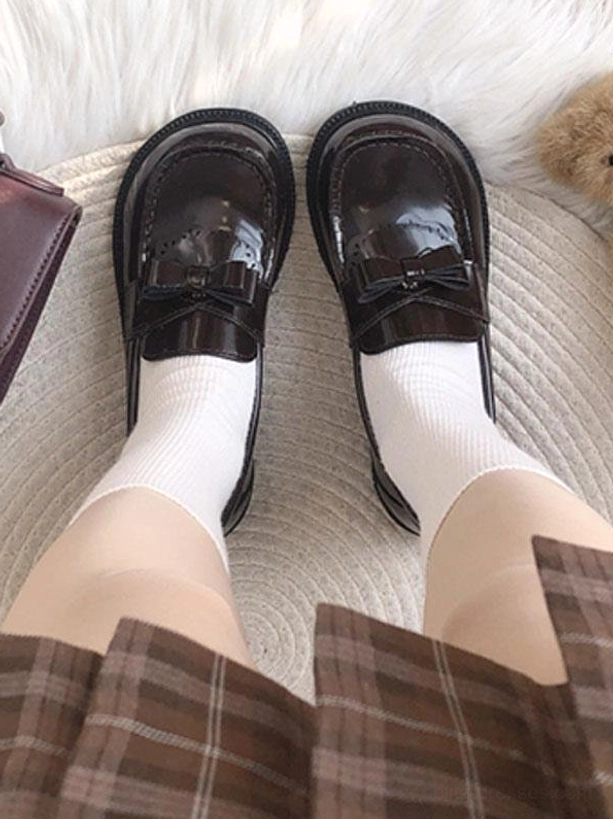Dark brown patent leather bow loafers overhead view with brown plaid skirt and white socks, chunky flat sole lolita loafers