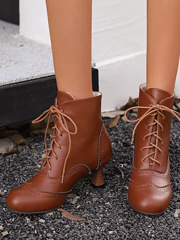 Brown vintage ankle boots shown in frontal flat view on female lower legs against gravel pavement, featuring lace-up closure, smooth leather material, and round toe design perfect for Lolita styling