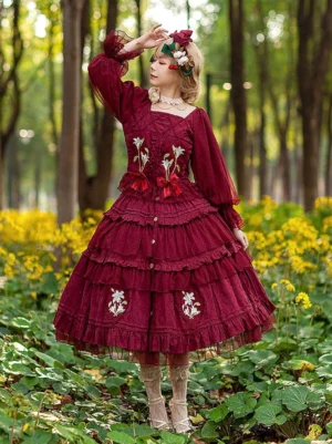 Burgundy Classic Lolita dress with floral embroidery worn outdoors in woodland flower field by model showing front full-body view with square neckline and layered ruffled skirt