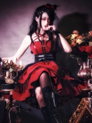 Burgundy and black Gothic Lolita jumper skirt dress with criss-cross lace-up halter straps and layered lace hem, shown on model from three-quarter angle in vintage indoor setting