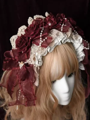 Burgundy Gothic Lolita pearl lace headband front three-quarter view featuring cream ruffled lace, burgundy fabric roses, and pearl chains on blonde wig mannequin