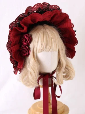Burgundy classic Lolita bonnet hat front view with eyelet lace ruffles, fabric roses, and wine red ribbon ties on mannequin with blonde bob