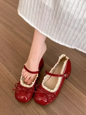Burgundy Mary Jane lolita shoes worn with white pleated skirt shown from overhead perspective, showcasing patent leather finish, round toe, bow decoration, and ankle buckle closure