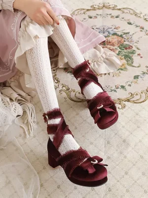 Burgundy rococo lolita footwear featuring crisscross satin ankle straps and rhinestone bow embellishment, side profile on vintage floral carpet with frilly dress