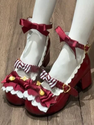Burgundy patent leather Mary Jane Lolita pumps with decorative red bows and heart gold buckles worn on feet with white sheer stockings front three-quarter view