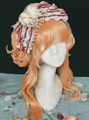 Burgundy Rococo lolita headdress with delicate lace bow and pearl chain accents, displayed on mannequin with orange curly wig, three-quarter front angle view showing intricate floral and lace details