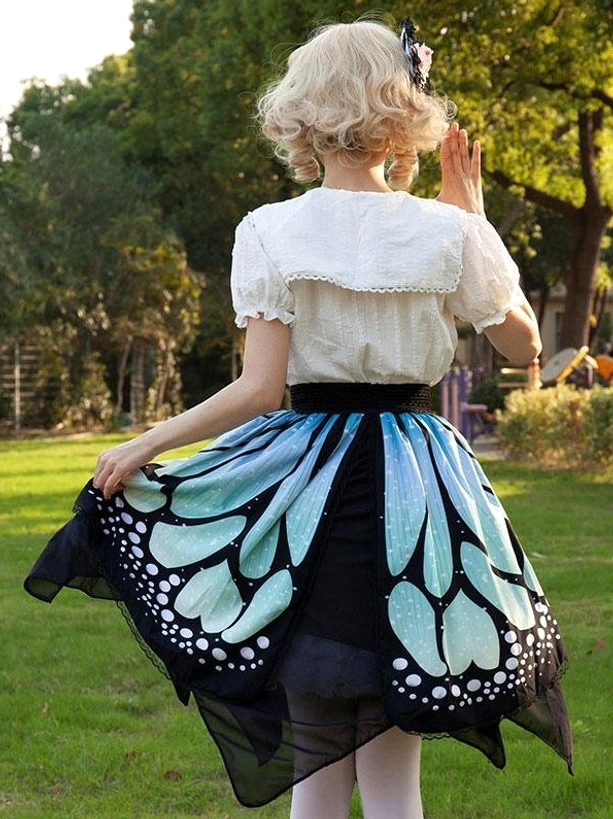Sweet lolita butterfly skirt rear full view in outdoor park setting showing back design, sheer black irregular hem edge, and butterfly print pattern in natural daylight