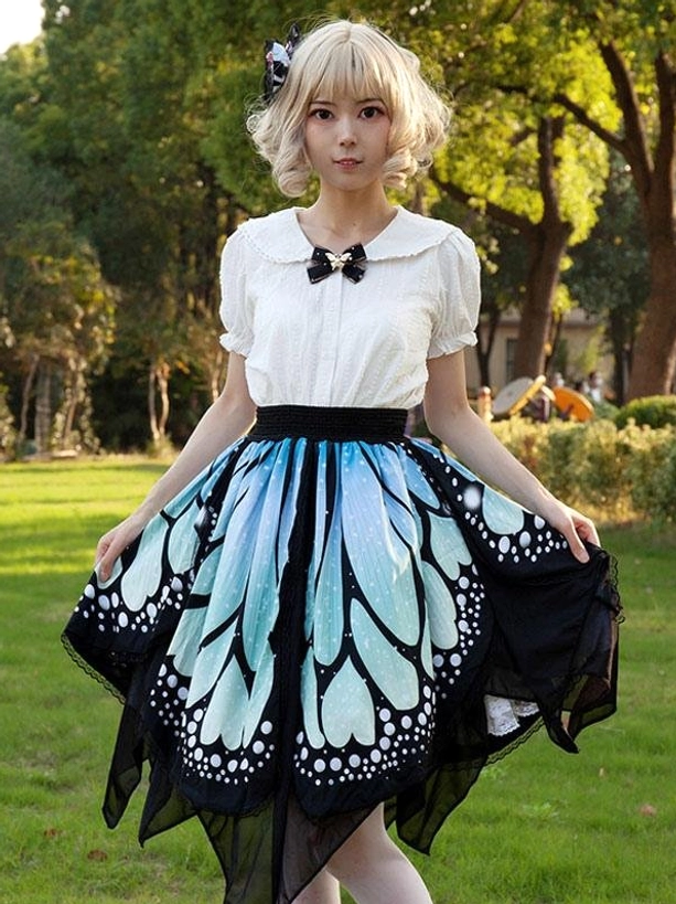 Sweet lolita butterfly half skirt front outdoor full view in park with green lawn and trees, model wearing white blouse, displaying layered irregular hem and blue butterfly pattern
