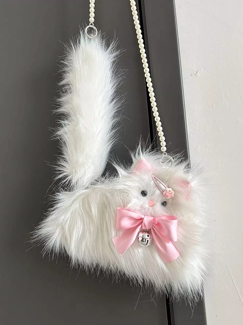 Hanging shot of plush cat crossbody bag against plain wall showcasing attached tail, pearl chain strap details, pink bow with silver bell, and complete silhouette