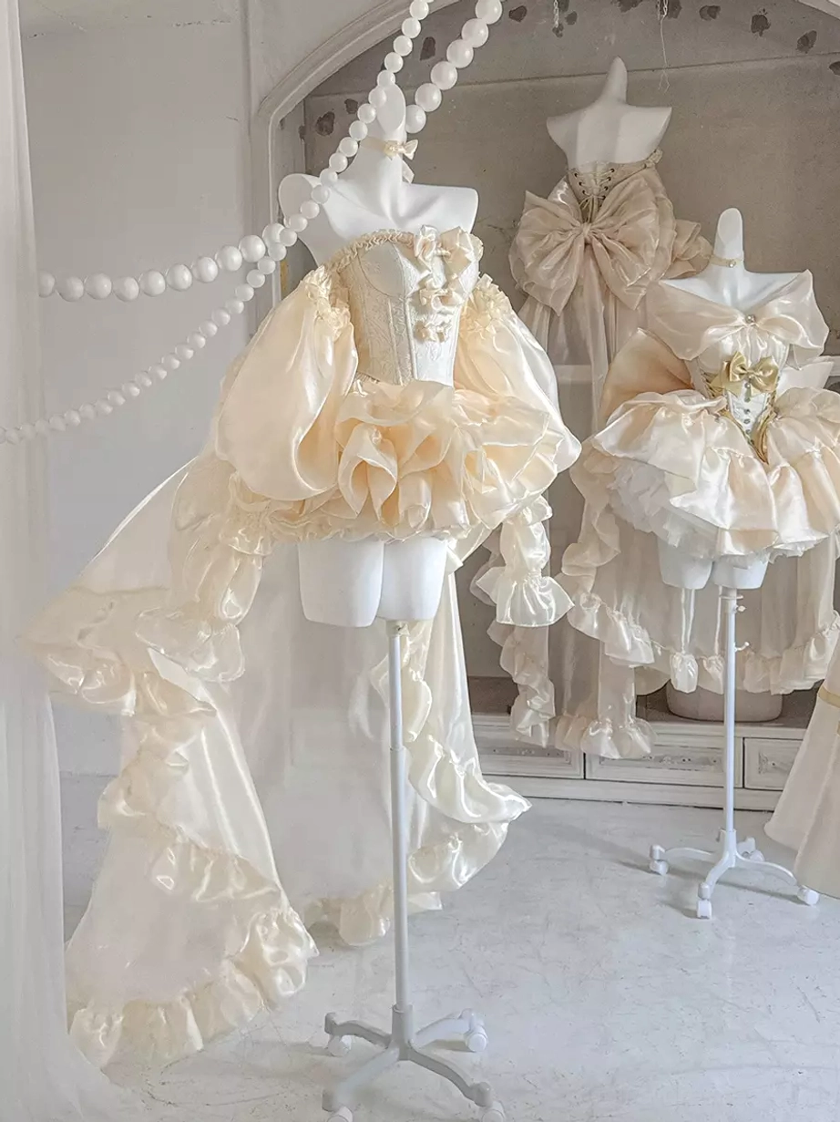Multiple champagne ballet lolita dresses displayed together with strapless corset designs, ruffled details, and long satin trains in studio setting