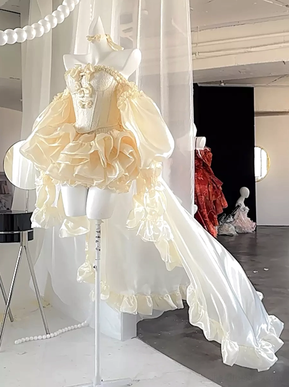 One-shoulder champagne ballet lolita gown with oversized ruffled back bow, long satin train, and theatrical fairy dress design, back three-quarter view