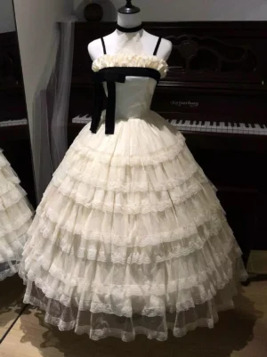 Champagne fairy lolita ball gown with spaghetti straps and black velvet bow on mannequin, featuring multi-layered ruffle tulle skirt and delicate piano background aesthetic