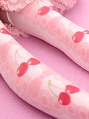 Close-up side view of sweet lolita stockings featuring soft velvet texture, red cherry motifs, lace bow patterns, and detailed print design against pink ruffled skirt backdrop