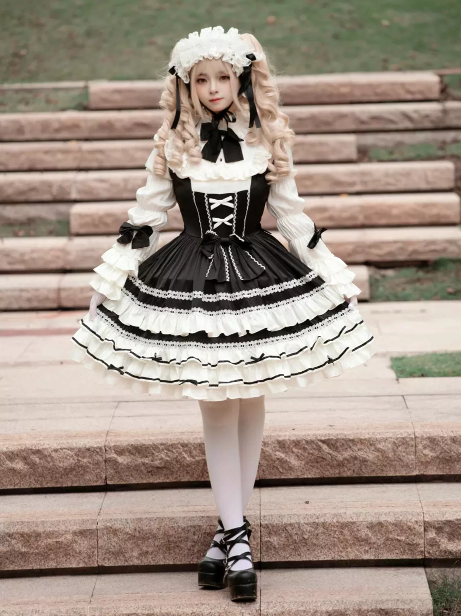 Black gothic lolita dress centered front view with blonde model displaying neat layered ruffled skirt design, structured silhouette outdoor stairs