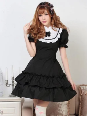 Classic black and white lolita op dress front view with puffed sleeves white lace collar black bow and layered ruffled skirt model wearing white printed stockings