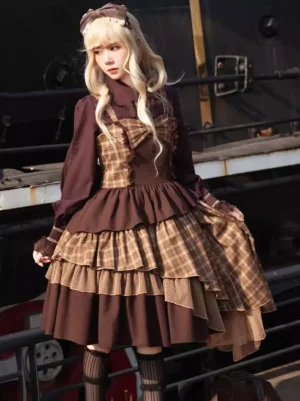 Classic brown plaid sleeveless lolita JSK dress front three-quarter view on blonde model wearing striped stockings at vintage train station