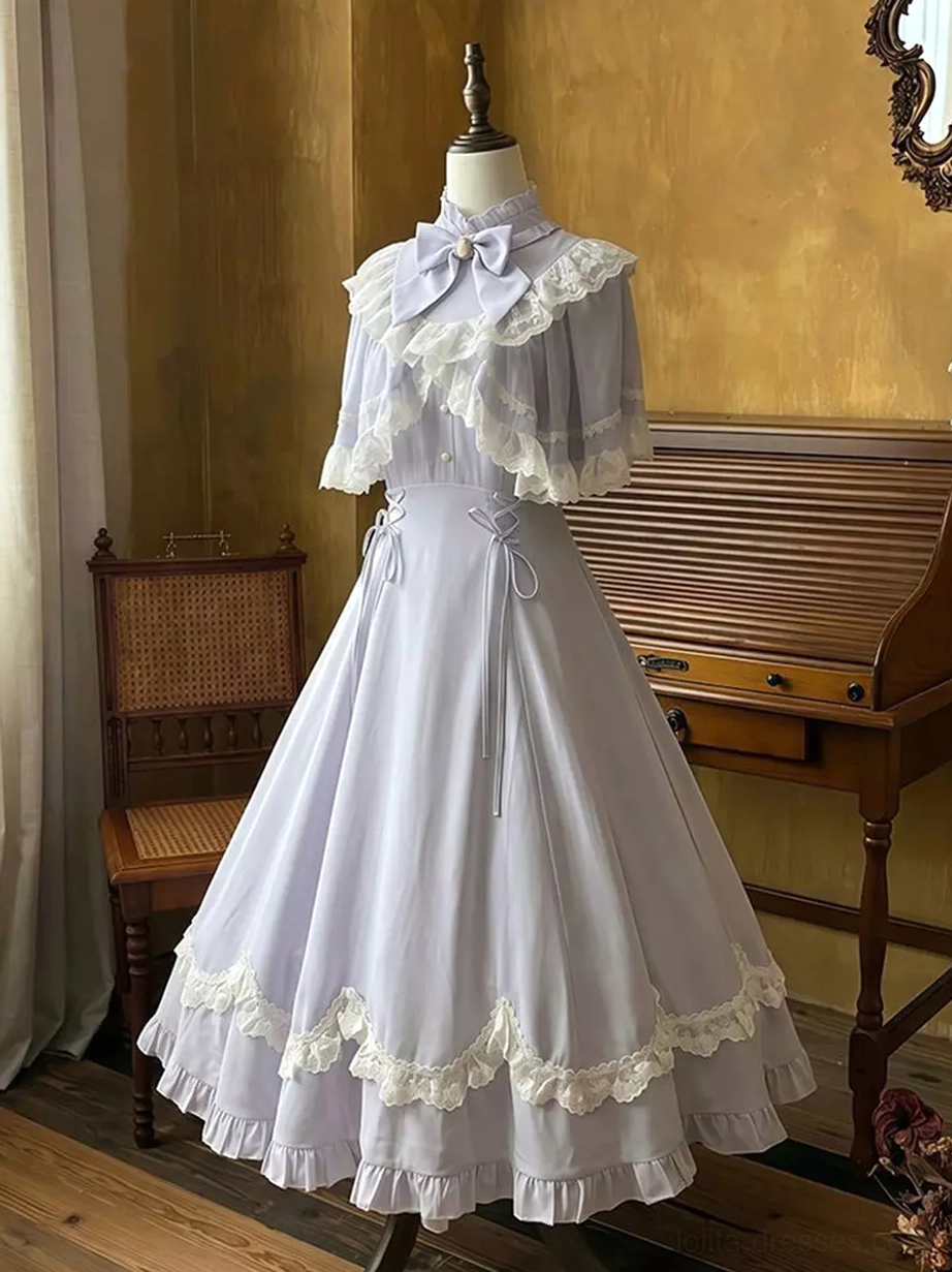 Classic lavender lolita maxi dress with lace capelet and neck bow, displayed on dress form in three-quarter front view showing delicate lace cape, drawstring waist details, and romantic A-line silhouette