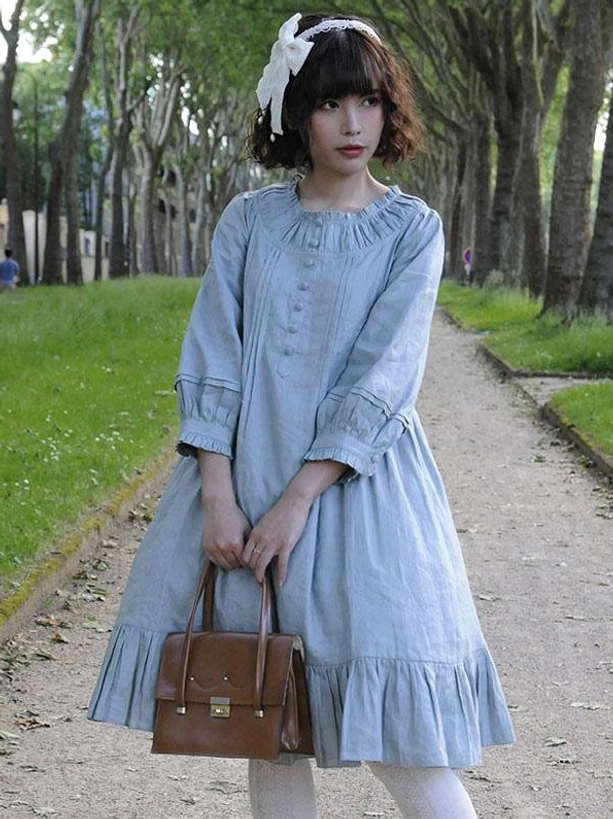Serene blue linen lolita dress featuring shirred round neckline with frills, front button decorations, ruffled 3/4 sleeves, and pleated ruffled skirt hem, outdoor park setting