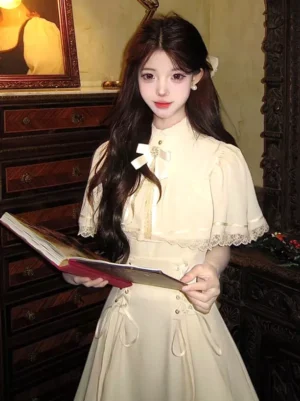 Classic lolita beige midi dress eye-level front view showcasing stand collar, lace-trimmed capelet sleeves, waist drawstring details, and ornamental brooch with bow accent on the chest