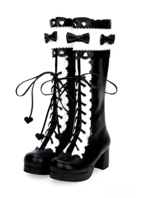 Classic lolita knee-high boots front view, black and white two-tone with lace-up fastening and heart-shaped lace pendant detail, round toe platform chunky heel