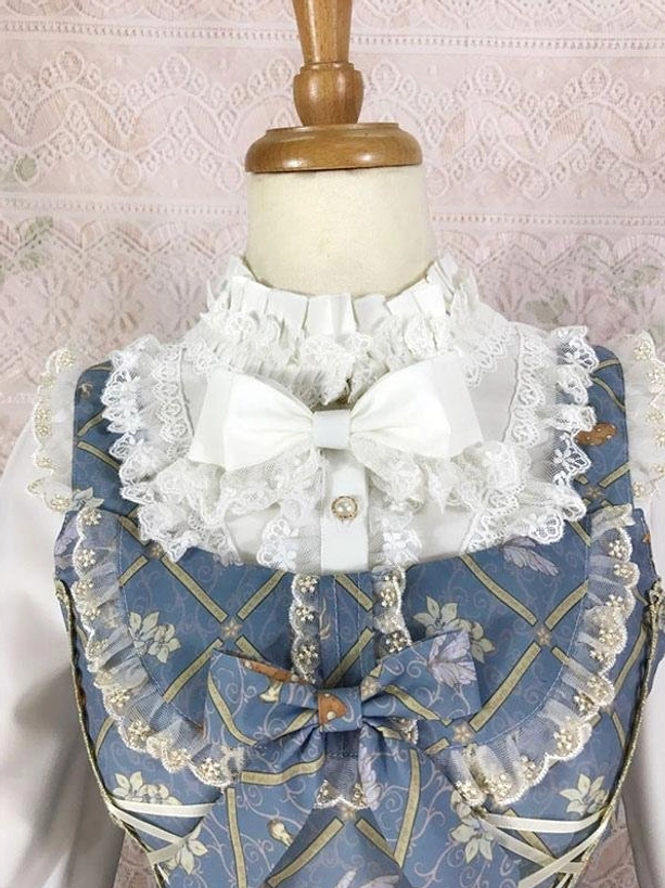 Close-up detail of classic lolita dress lace ruffled collar and large white decorative bow embroidered blue fabric embellishment