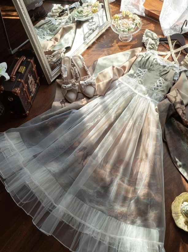 Flat lay top-down view of classic lolita dress with cross strap design, sheer tulle overlay, landscape print skirt, and ruffled hemline on neutral background