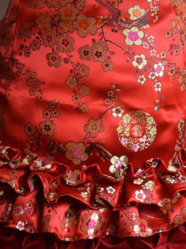 Red satin lolita dress bodice and skirt ruffle sections showing intricate plum blossom floral brocade print and layered ruffled edges texture
