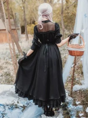 Black lolita OP dress back view showing sheer mesh upper panel waist ribbon and ruffled hem on model with wicker basket in outdoor vintage setting