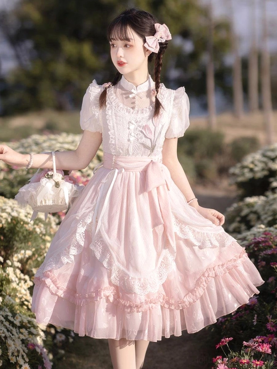 Pink classical lolita dress side three-quarter view stand collar waist bow handbag outdoor garden setting
