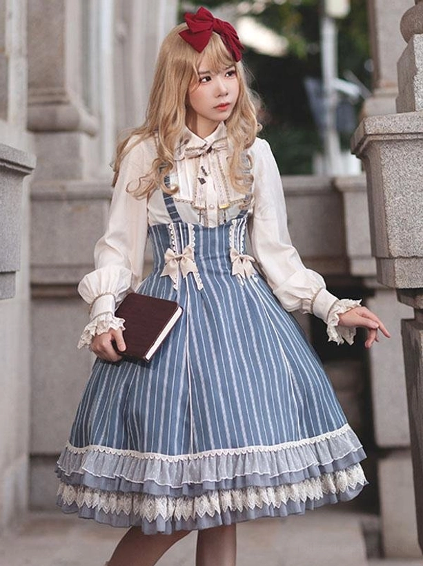 Sky blue striped classic lolita jumper dress with bow details worn outdoors, front three-quarter view showing vertical stripes and lace-trimmed hem