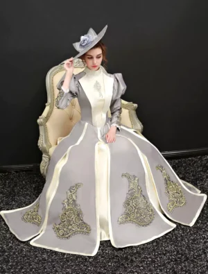 Victorian Classic Lolita formal gown seated view on model with decorative top hat, showing trailing skirt and matching embroidery details in vintage setting