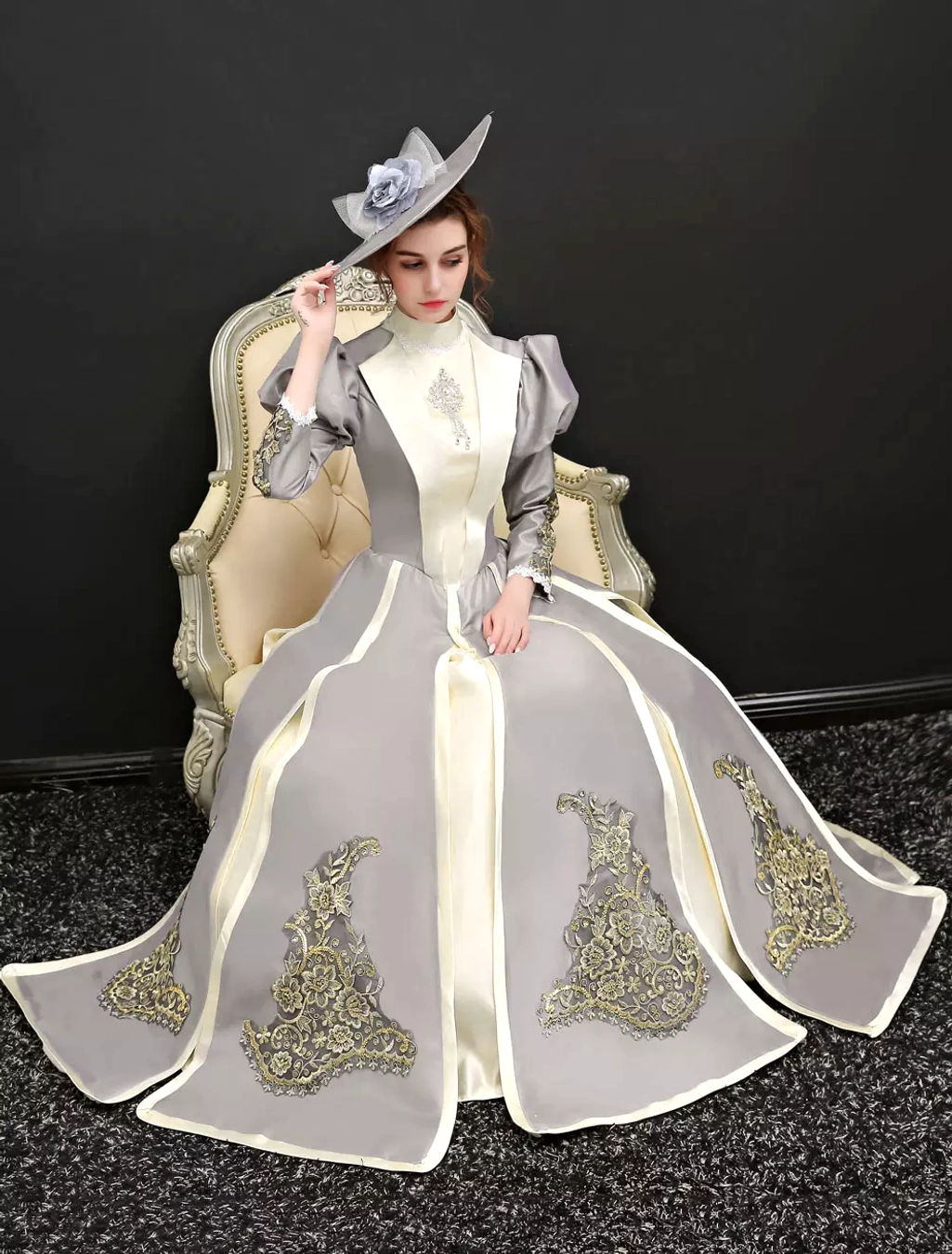 Victorian Classic Lolita formal gown seated view on model with decorative top hat, showing trailing skirt and matching embroidery details in vintage setting