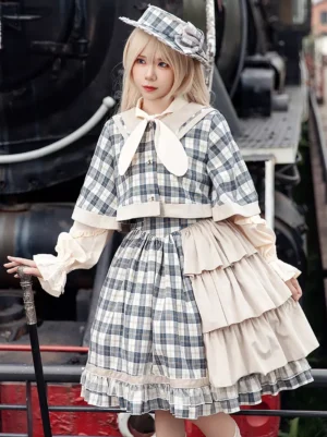 Three-quarter front view of plaid lolita poncho cape ensemble with matching detective hat and walking cane accessory showing layered ruffled skirt design