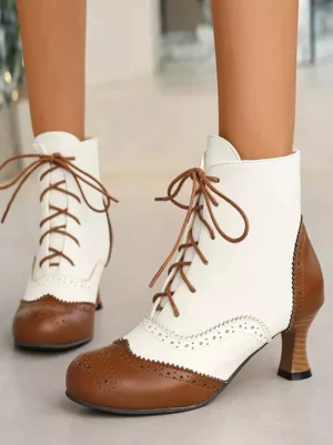 Classic vintage two-tone lolita ankle boots with brown and white color block design, round toe shape, brogue perforated details, and chunky wooden heel displayed on female lower legs showing front eye-level view
