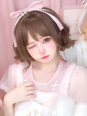 Coffee brown short curly Sweet Lolita wig styled on model wearing pink lace outfit with air bangs and pearl hairband, front close-up view